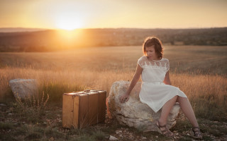 Woman sitting rock sunset beach - a suitcase in front free wallpaper