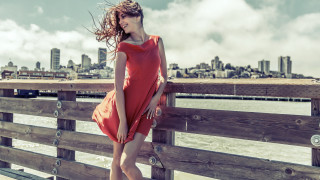 Woman red dress fence water 2 - a city in the background free wallpaper