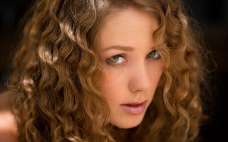 Woman curly hair serious portrait - her face and shoulder free wallpaper