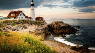 Lighthouse rocky cliff ocean cloudy 2 - a body of water below free wallpaper