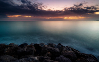Rocky shore sunset water mountains - rich moody colour free wallpaper