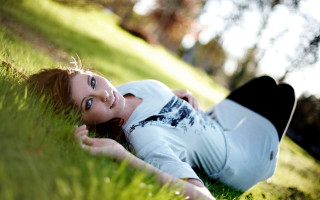 Woman laying in grass smiling - the grass free wallpaper