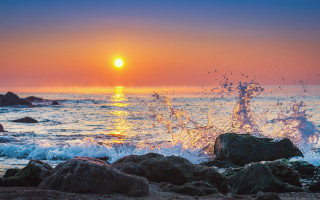 Sunset ocean wave rocks beach - a surfboard free wallpaper
