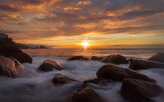 Sunset ocean rocks lighthouse clouds - a sunset over the ocean free wallpaper
