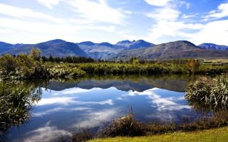 Lake mountains grass clouds sky - a few tree and bushes free wallpaper