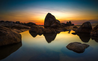 Sunset water rocks building sky - the foreground and a building in the background free wallpaper