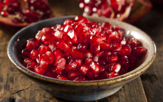 Pomegranate bowl wooden table closeup - a wooden table top free wallpaper