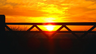 Sunset beach wooden fence grass - the foreground and a body of water free wallpaper