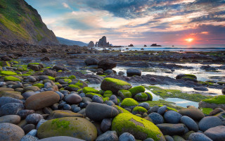 Rocky mossy beach sunset horizon - a rock formation in the foreground free wallpaper