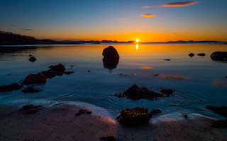 Sunset water rocks clouds lighthouse - a sunset over a body of water free wallpaper