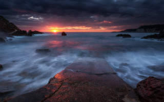Sunset ocean rocks sky lighthouse - the foreground and a body of water free wallpaper
