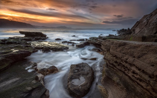 Rocky beach sunset clouds ocean - flowing free wallpaper for desktop