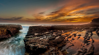 Sunset rocky beach water cliff 3 - a sunset over a rocky beach free wallpaper