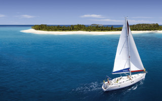Sailboat ocean island cloudy sky - a small island in the background free wallpaper