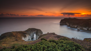 Sunset cliff lighthouse water beach - a body of water below free wallpaper