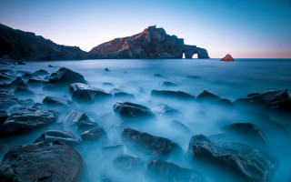 Rocky beach mountain horizon water - a rock formation in the foreground free wallpaper