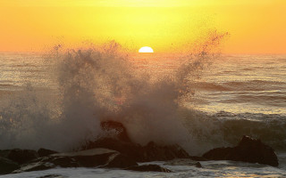 Crashing wave sunset rock ocean - the sun in the distance behind free wallpaper