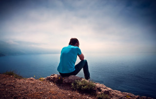 Man sitting rock ocean cloudy 2 - allen tupper true free wallpaper