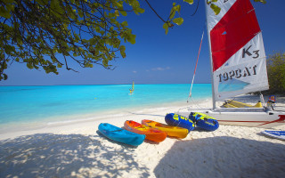 Beach kayaks sailboat sky ocean - vibrant colour free wallpaper