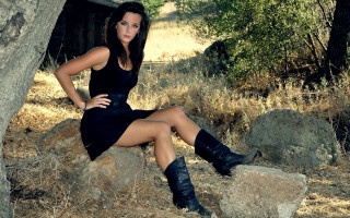 Woman black dress rock field 2 - tree and bushes behind her free wallpaper