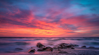 Sunset ocean rocks boat city - the foreground and a boat in the distance free wallpaper