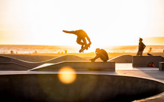 Skateboarder flying sunset beach ocean - sunrise time free wallpaper