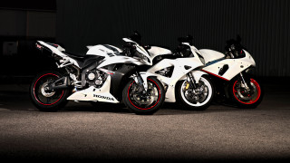 Motorcycles parked dark room pearlescent - a wall behind them free wallpaper