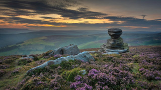 Rock formation grassy hill purple - the foreground and a sunset in the background free wallpaper
