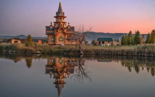 Wooden church reflection sunset mountains - the water of a lake free wallpaper