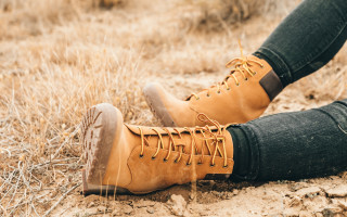 Person brownboots blackpants crossedlegs drygrass - dry free wallpaper