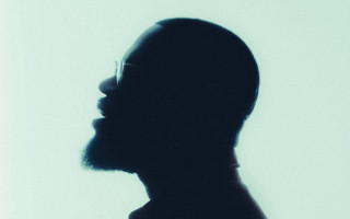 Bearded man glasses dark room - a white wall behind free wallpaper