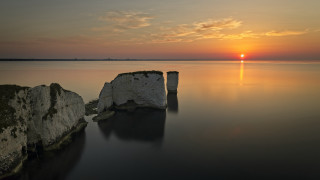 Sunset water rocks island clouds 2 - a small island in the background free wallpaper