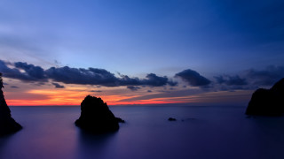 Sunset water rocks clouds city - a sunset over a body of water free wallpaper