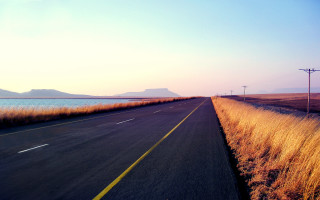 Road water mountain beach sunset - a mountain range in the distance free wallpaper