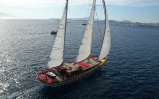 Sailboat red sail distant mountain - a sailboat free wallpaper