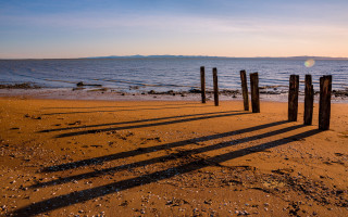 Wooden posts beach sunset ocean - sandy free wallpaper