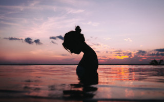 Woman water sunset silhouette tranquil - the sun setting behind her free wallpaper