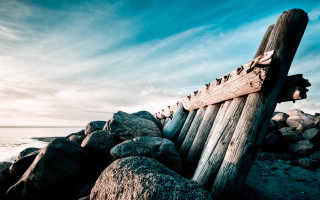 Wooden boat rocky beach ocean - depth of field free wallpaper
