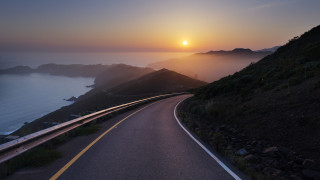 Sunset road water hill mountain - a sunset in the background and a body of water free wallpaper