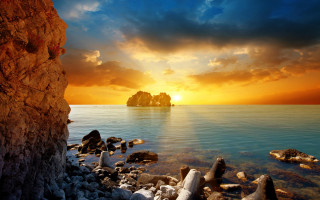 Sunset rocky beach island foreground - a small island in the distance free wallpaper