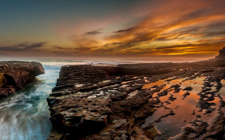 Sunset rocky beach water cliff 2 - a sunset over a rocky beach free wallpaper
