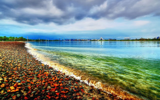 Beach water city clouds sunset - a city in the distance free wallpaper