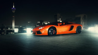Bright orange sports car city - a city skyline in the background free wallpaper