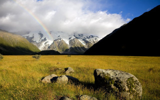 Rainbow mountains grassy field landscape - a grassy field in the foreground free wallpaper