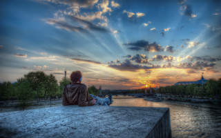 Sunset river ledge person boats - the water and a building in the background free wallpaper