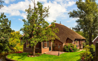 Thatched roof house garden river - a river and trees free wallpaper