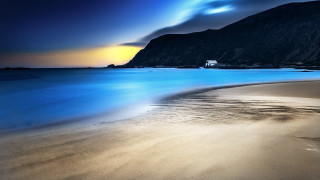 Beach mountain shore water boat - a mountain in the background and a body of water free wallpaper