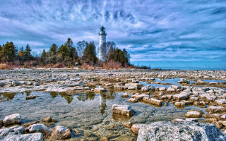 Lighthouse rocky shore trees water - free winter wallpaper