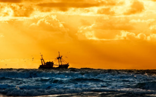 Boat ocean yellow sky clouds 2 - a sunbeam in the distance free wallpaper