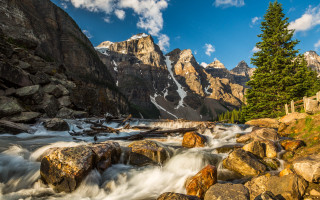 Mountain stream rocks trees snowy - the foreground and a mountain range in the background free wallpaper